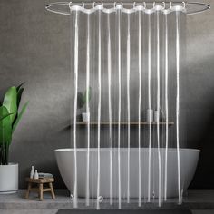 a white tub sitting next to a green plant in a bathroom under a shower curtain