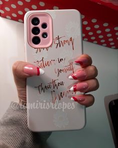 a woman holding up her phone case with red and white nail polishes on it