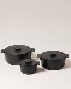 three black pots and pans sitting next to each other