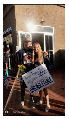 a man and woman holding a sign in front of a building