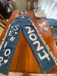 a pair of jeans with the word love spelled on them sitting on top of a wooden table