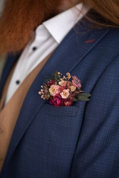 a man wearing a blue suit with flowers on his lapel and a white shirt