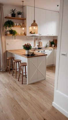 an open kitchen with white cabinets and wooden flooring is seen from the doorway to the dining room