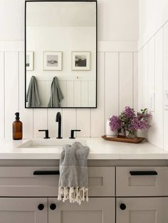 a white bathroom with two sinks and a large mirror on the wall above it's counter