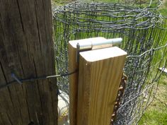 a wooden post is in front of a fence with barbed wire around it and an electric box on the other side