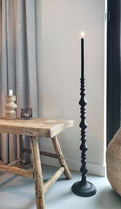 a black candle stands next to a table with a wooden bench in front of it