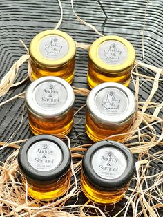 four jars of honey sitting on top of straw