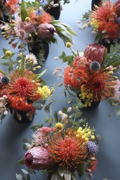 many different types of flowers are arranged in vases on a table with blue surface