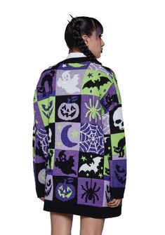 a woman is wearing a purple and green sweater with halloween decorations on it, while she has her back turned to the camera