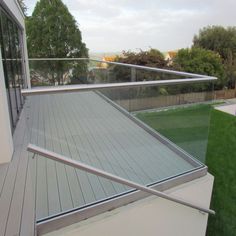 an outdoor deck with glass railings and grass