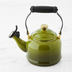 a green tea kettle with a black handle