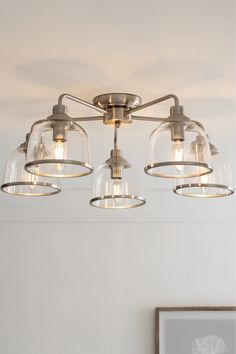 a light fixture with three glass shades hanging from the ceiling in a white walled room