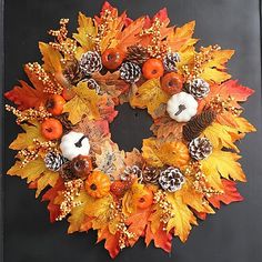 a wreath with pine cones, pumpkins and acorns is hanging on a door