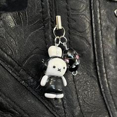 a black leather purse with a keychain that has a white rabbit on it