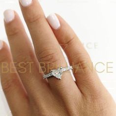 a woman's hand with a diamond ring on top of her finger and white nails