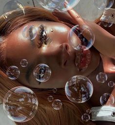 a woman with red hair is surrounded by soap bubbles in the air and her eyes are closed