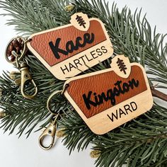 two leather keychains with name tags on them hanging from a christmas tree branch