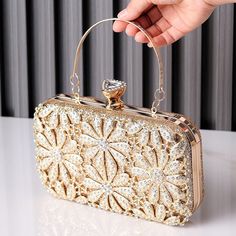 This clutch is a masterpiece of sheer elegance, boasting exquisite details that captivate the eye. From the delicate petals to the sparkling rhinestones that dance with every step, it's a symphony of beauty. Not only is it stunning, but it's also practical, lightweight, and easy to carry, ensuring you move gracefully through the night. With this clutch, beauty merges seamlessly with functionality, creating an unforgettable experience. Now available in gold and black. Chic Crystal Bags For Events, Chic Evening Crystal Bags, Chic Crystal Evening Bag For Events, Rectangular Sparkling Evening Clutch, Glamorous Gold Sparkling Clutch, Evening Bags With Crystal Material, Embellished Crystal Clutch For Evening, Embellished Crystal Evening Clutch, Sparkling Evening Clutch Bag