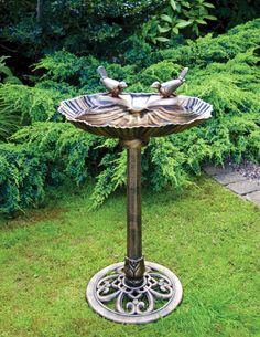 a bird bath sitting on top of a metal stand in the middle of some grass