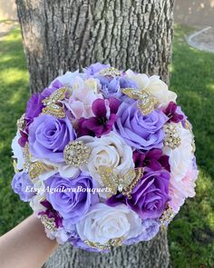 the bride's bouquet was made up of purple and white roses, gold brooches