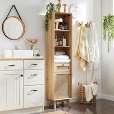 a bathroom with white cabinets and towels on the shelf next to it is also decorated with greenery