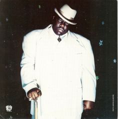 a man in a white suit and hat holding a cane