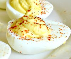 deviled eggs on a white plate with red sprinkles and seasoning