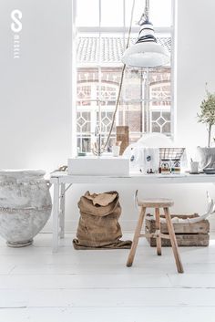 a white room with various vases and other items on the table in front of an open window