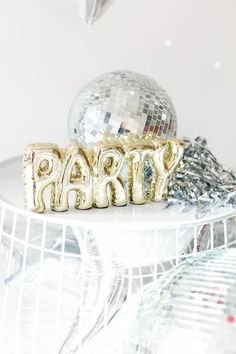 the word party spelled out in gold letters on top of a white plate with silver foil