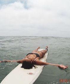 a woman laying on a surfboard in the ocean