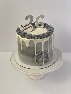 Grey cake with white drip. Swirls of buttercream surround the top of the cake with a silver “26” in the middle and a happy birthday plaque. On the bottom right is a silver Mercedes logo. Cakes For Men 26th Birthday, Cake For Car Lover Men, Car Themed Birthday Cake For Men, 26 Birthday Cake For Him, Car Theme Cake For Men