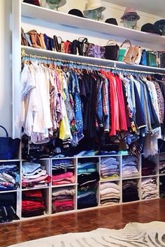 a closet filled with lots of different types of clothes and hats on shelves next to a bed