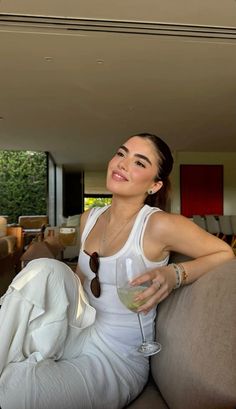 a woman sitting on top of a couch holding a wine glass in her right hand