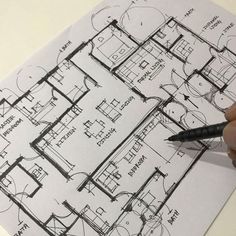 a hand is holding a pen and drawing a floor plan