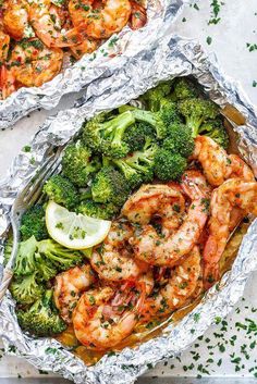 shrimp and broccoli wrapped in tin foil with lemon wedges on the side