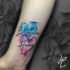 a heart tattoo on the arm with words written in it and watercolor splashes