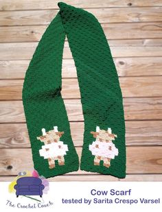 the cow scarf is made with green yarn and has a small white sheep on it