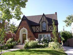 a house that is in the middle of some bushes and flowers on the front lawn