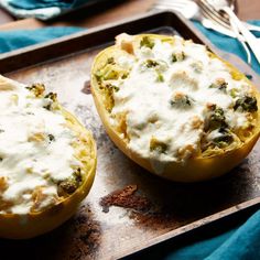 two stuffed squash halves with cheese and broccoli in them on a baking tray