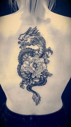 a woman's back with a dragon and flowers tattoo on her left side ribcage