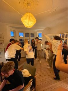 a group of people standing in a living room with one person holding a cell phone