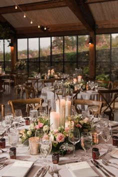 a table set up with candles, flowers and napkins for an elegant wedding reception