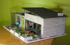 a model house sitting on top of a wooden table next to a green painted wall