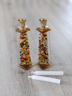 two glass candlesticks sitting on top of a wooden table next to each other