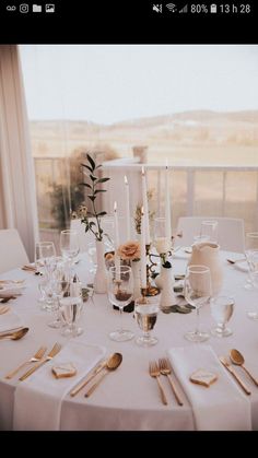 the table is set with white linens and gold cutlery, candles, and flowers