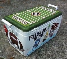 a cooler sitting on top of a cement ground covered in stickers and writing that reads, follow me to the football field