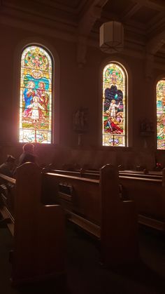 three stained glass windows in a church with pews and people sitting at the alter