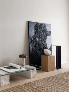 a living room with a glass table and art on the wall