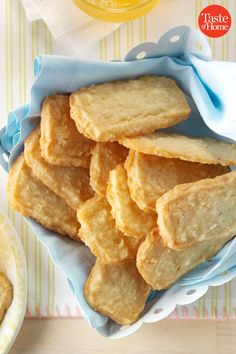 some cookies are in a blue bowl on a table next to a glass of orange juice