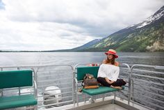 a woman is sitting on a boat in the water with her feet up and wearing a hat